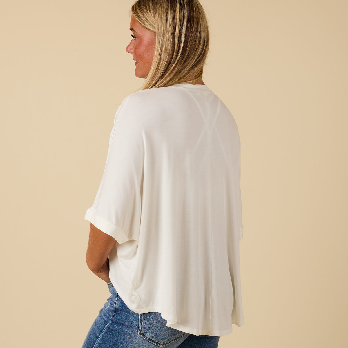 Model wearing hi lo white short sleeve top with relaxed fit, shown from back