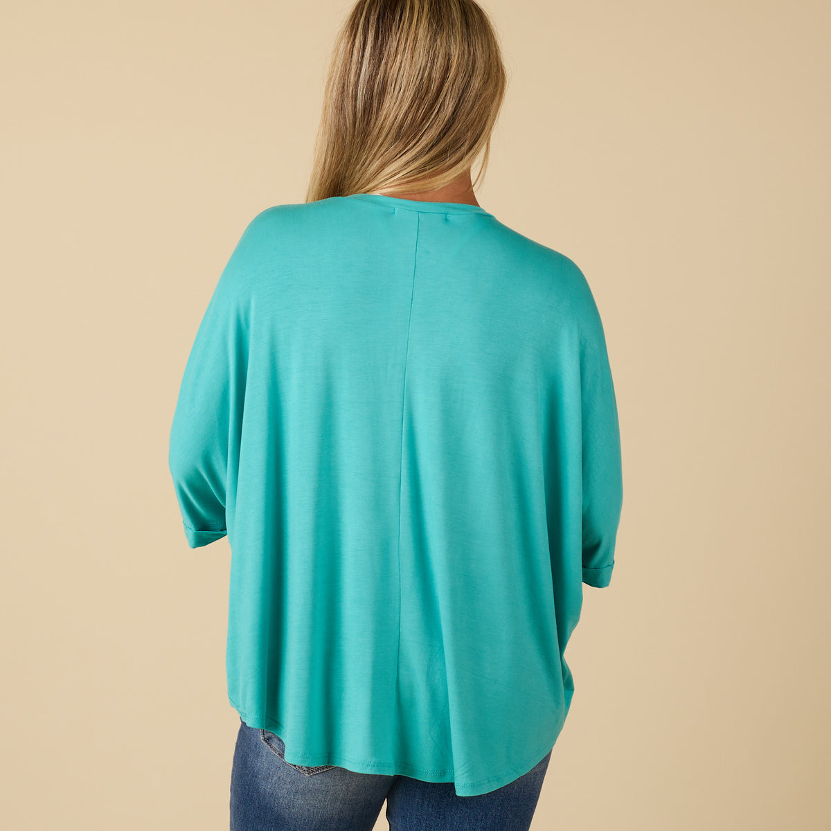Model wearing hi lo seafoam short sleeve top with relaxed fit, shown from back