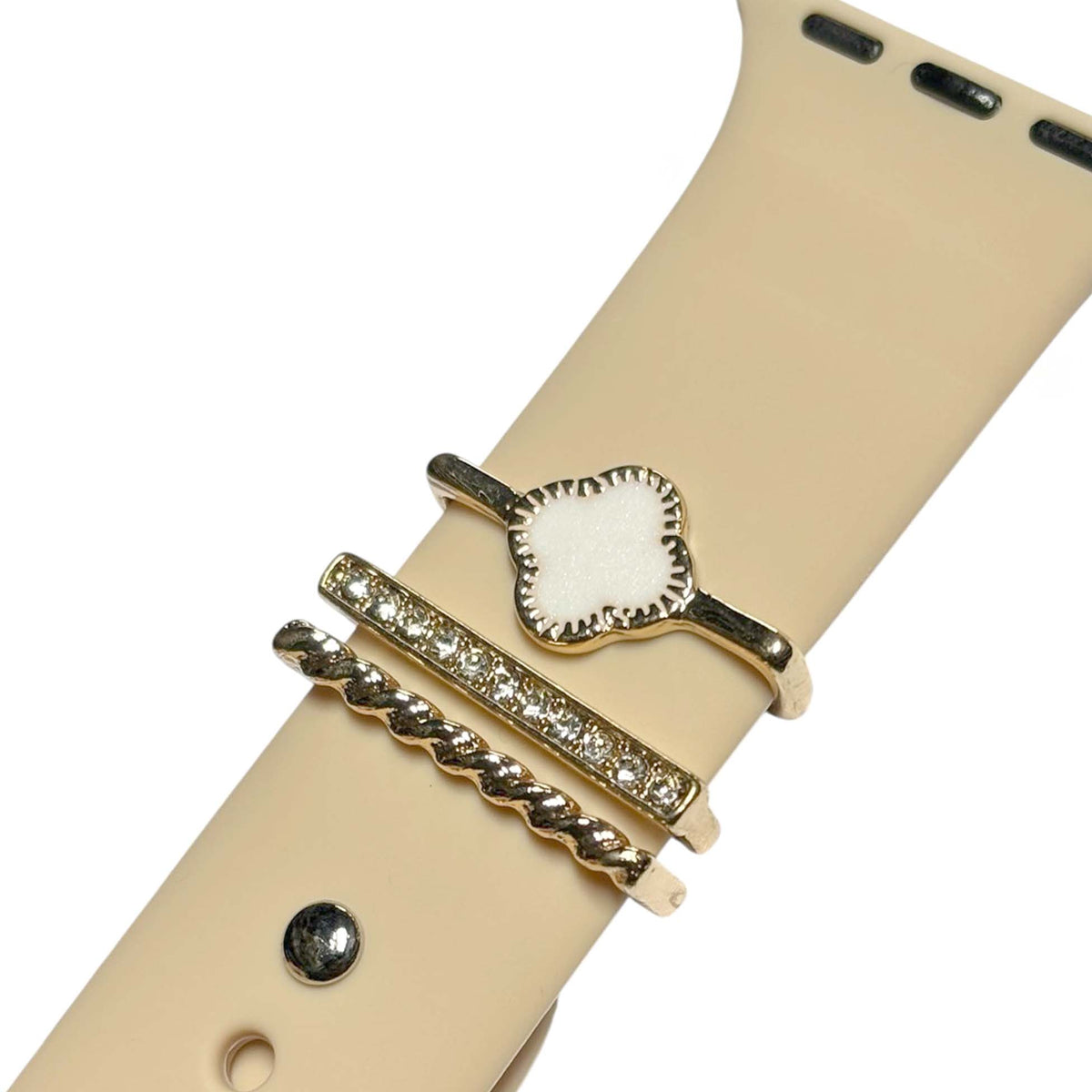 Beige Palmetto Moon Apple Watch band with gold accent rings featuring a white clover charm, rhinestone bar, and rope twist design.
