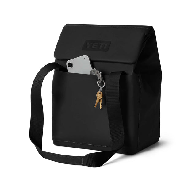 Close-up of black tote back pocket holding a phone, keys, and keychain with YETI logo.