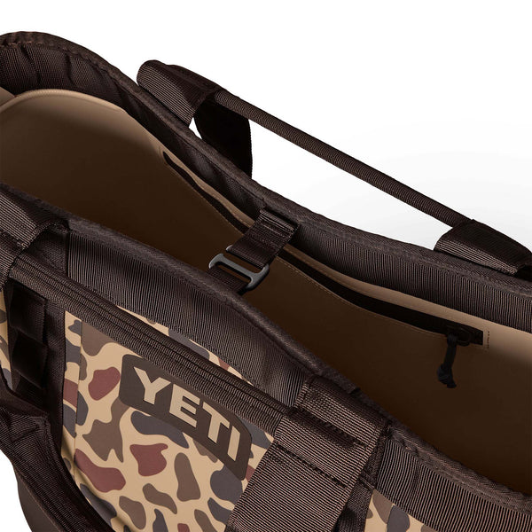 Close-up of tote opening showing durable nylon handles and buckle closure over top zipper pocket.