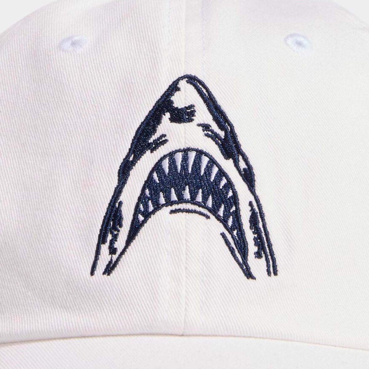Close-up of Vineyard Vines white cotton cap with navy embroidered shark mouth design on the front.