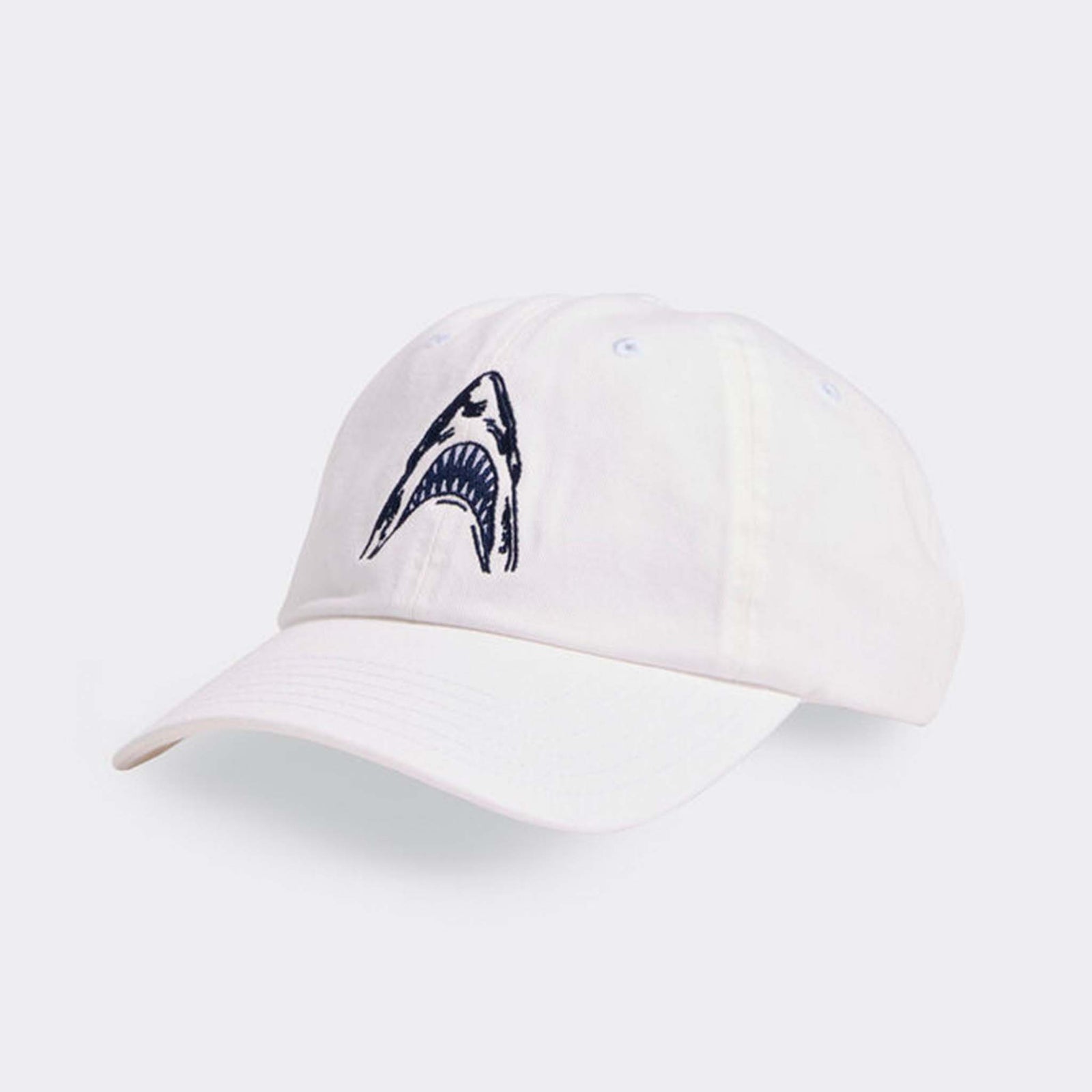Angled front view of Vineyard Vines white cap featuring navy shark mouth embroidery and curved brim.