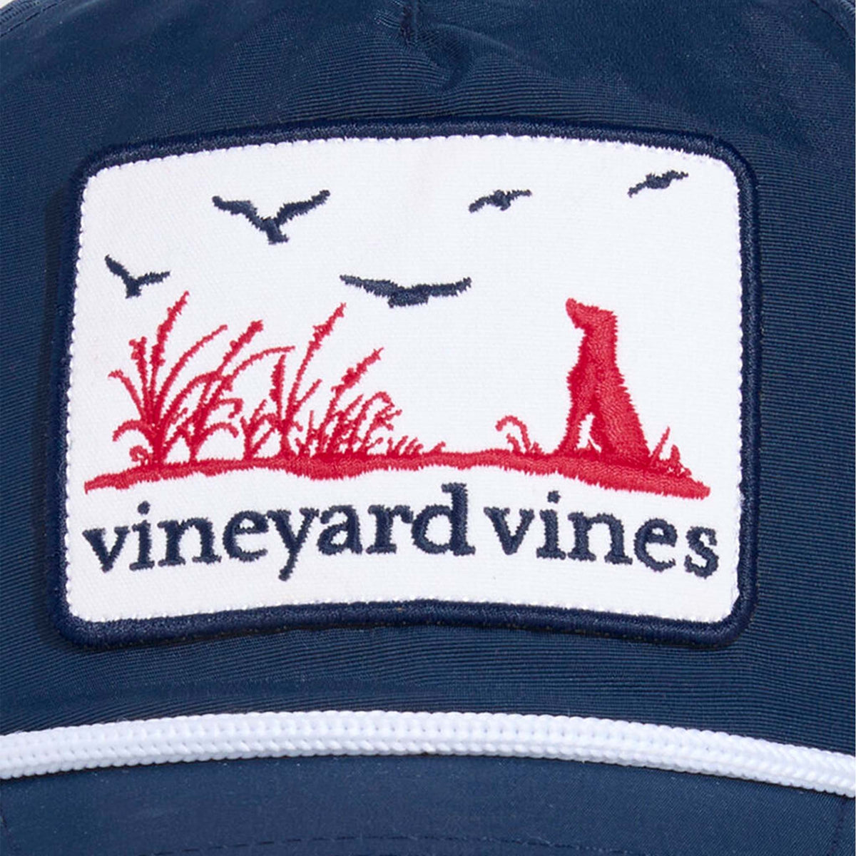 Vineyard Vines Dog Patch Hat in Moonshine with embroidered red dog, marsh grass, and birds above navy “vineyard vines” text.
