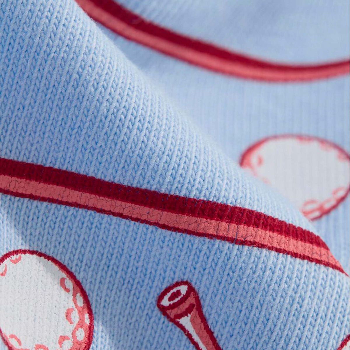 Close-up of a light blue fabric with red stripes and white circular patterns.