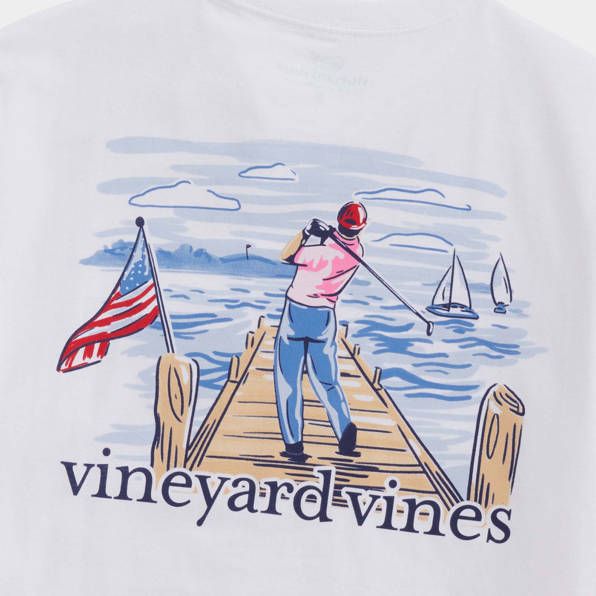 T-shirt with a graphic of a person on a dock, American flag, and sailboats, featuring the 'Vineyard Vines' brand.