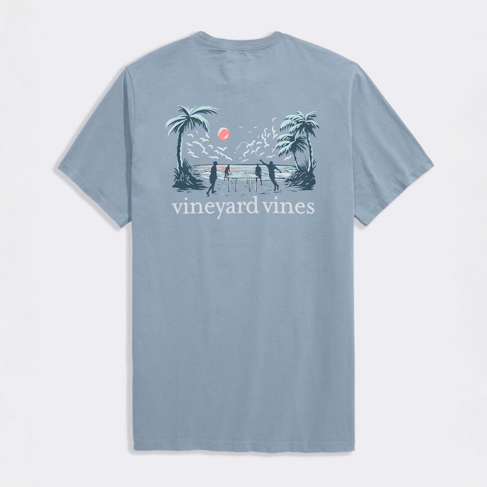 Back view of light blue Vineyard Vines t-shirt featuring beach scene graphic with palm trees, ocean sunset, and players around a table.