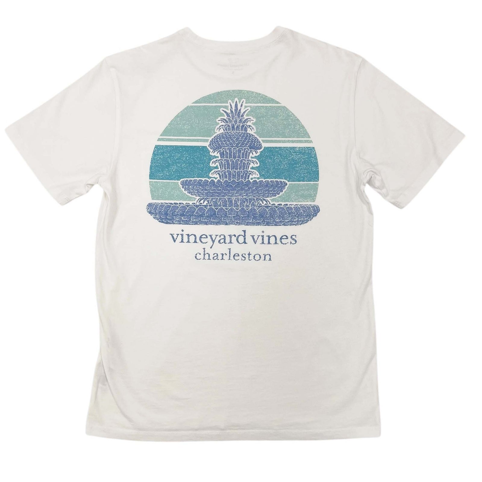 Back view of Vineyard Vines short sleeve t-shirt, Color white, unisex sizes XS-XXL, 100% cotton. This Vineyard Vines short sleeve t-shirt features a blue sketch-style illustration of Charleston's Pineapple Fountain. Aqua-colored accents are the backdrop behind the fountain. Below the design, the Vineyard Vines logo and the word 'Charleston' are printed.