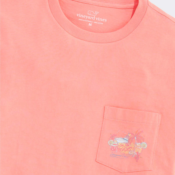 Coral-colored t-shirt with a pocket featuring a colorful graphic design, branded with 'Vineyard Vines'.