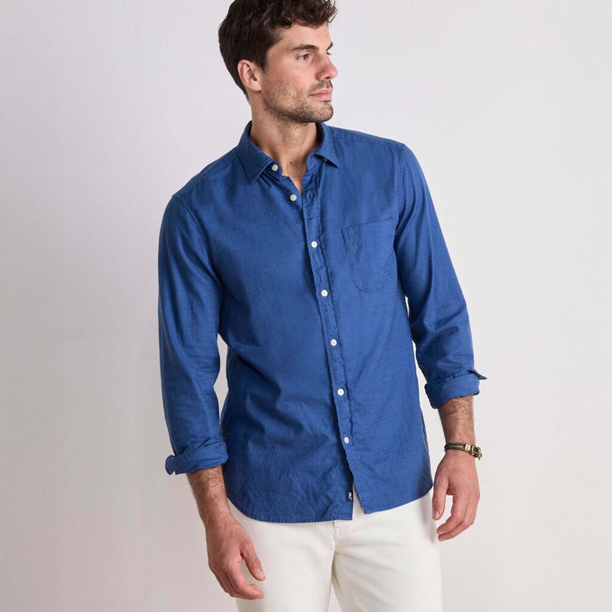 Model wearing Vineyard Vines solid Moonshine blue long sleeve button-down shirt with rolled sleeves.