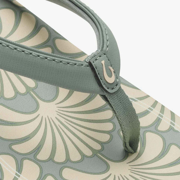 Close-up of a sandal with floral pattern and green strap on a white background