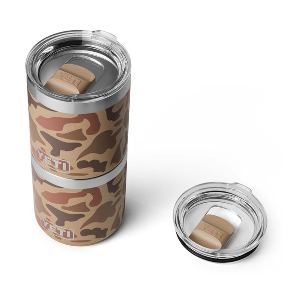 Top-down angle showing two stacked YETI Wetlands Camo mugs with tan MagSlider lids, next to a separate matching lid on the side.