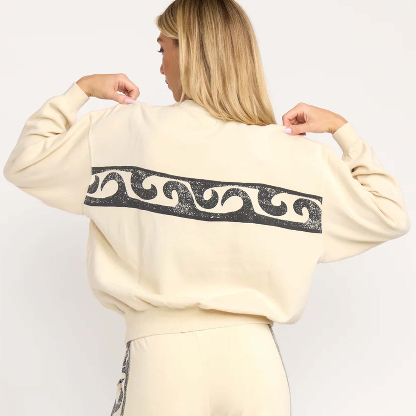 Back view of cream Billabong sweatshirt with large black wave pattern graphic across the back.