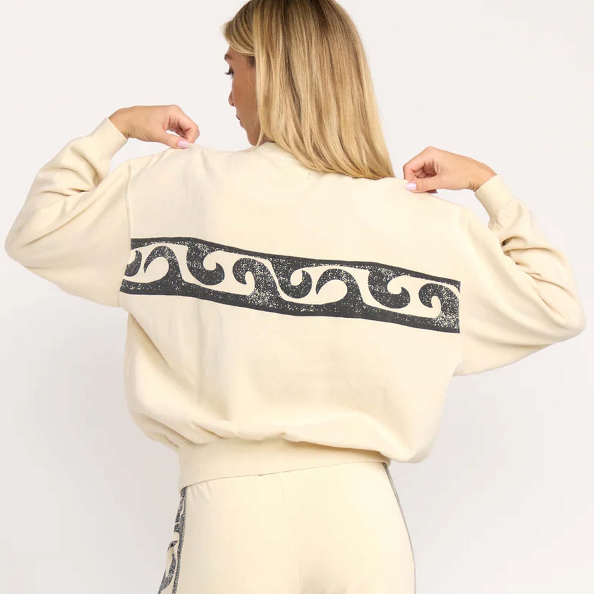 Back view of cream Billabong sweatshirt with large black wave pattern graphic across the back.