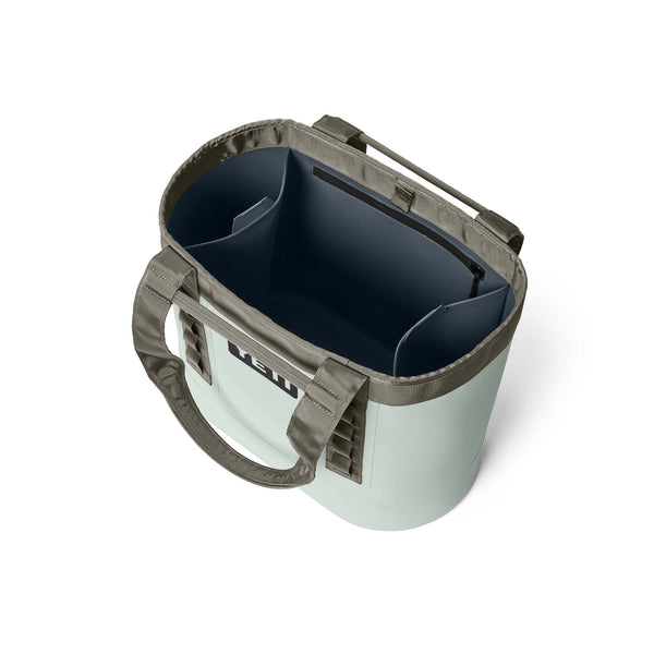 Angled top down view of YETI two toned green camino bag with built in pockets shown open.