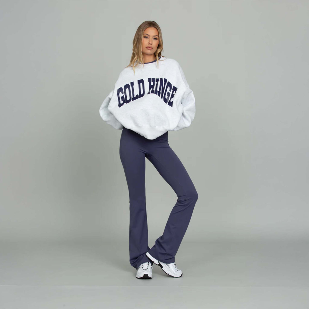 Model wearing Gold Hinge Fold Over Flare Leggings in indigo with oversized white sweatshirt.