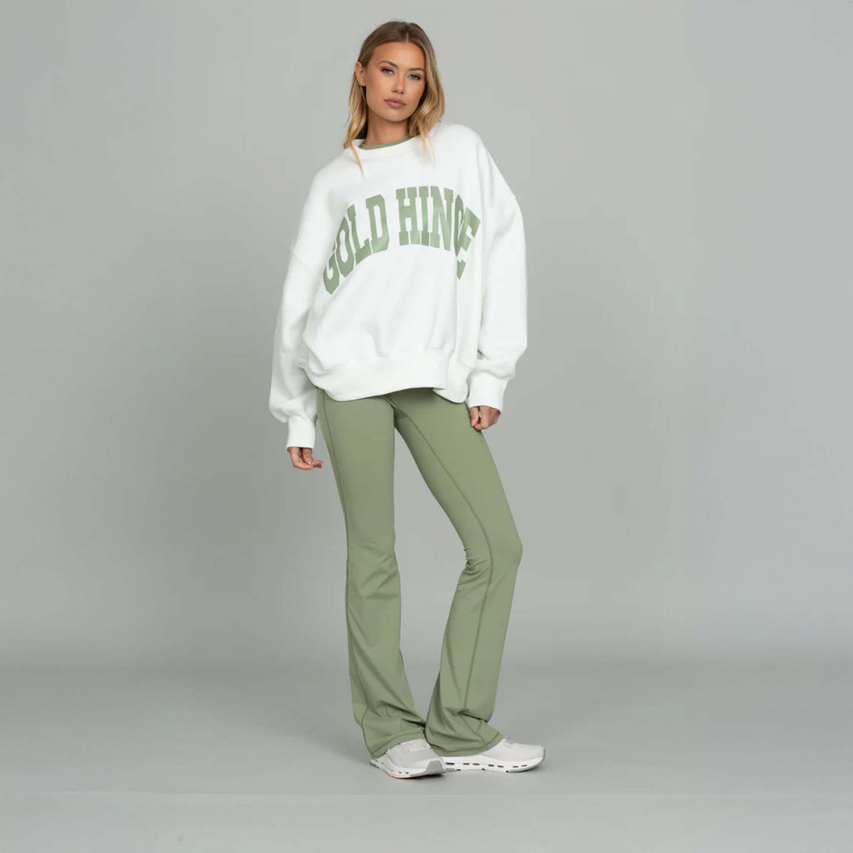 Model wearing Gold Hinge Fold Over Flare Leggings in light green with oversized white sweatshirt.
