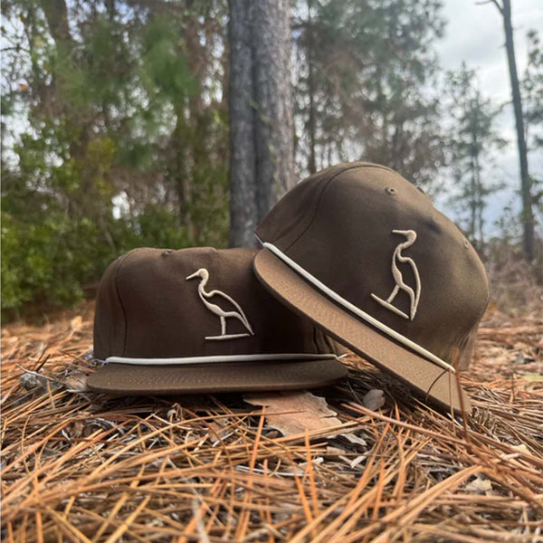 Brown hat with a cream embroidered heron on the front and a cream rope accent on the bill