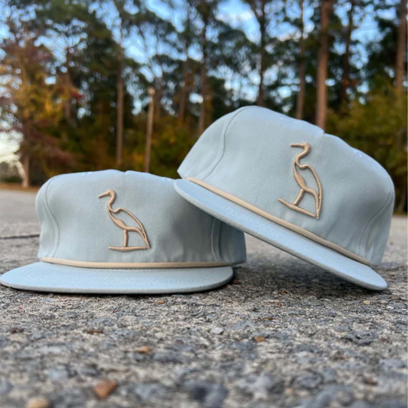 light blue hat with ivory embroidered heron on the crown and rope across the bill.