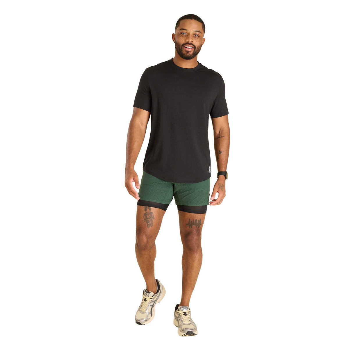 Man wearing a black t-shirt and green shorts on a white background