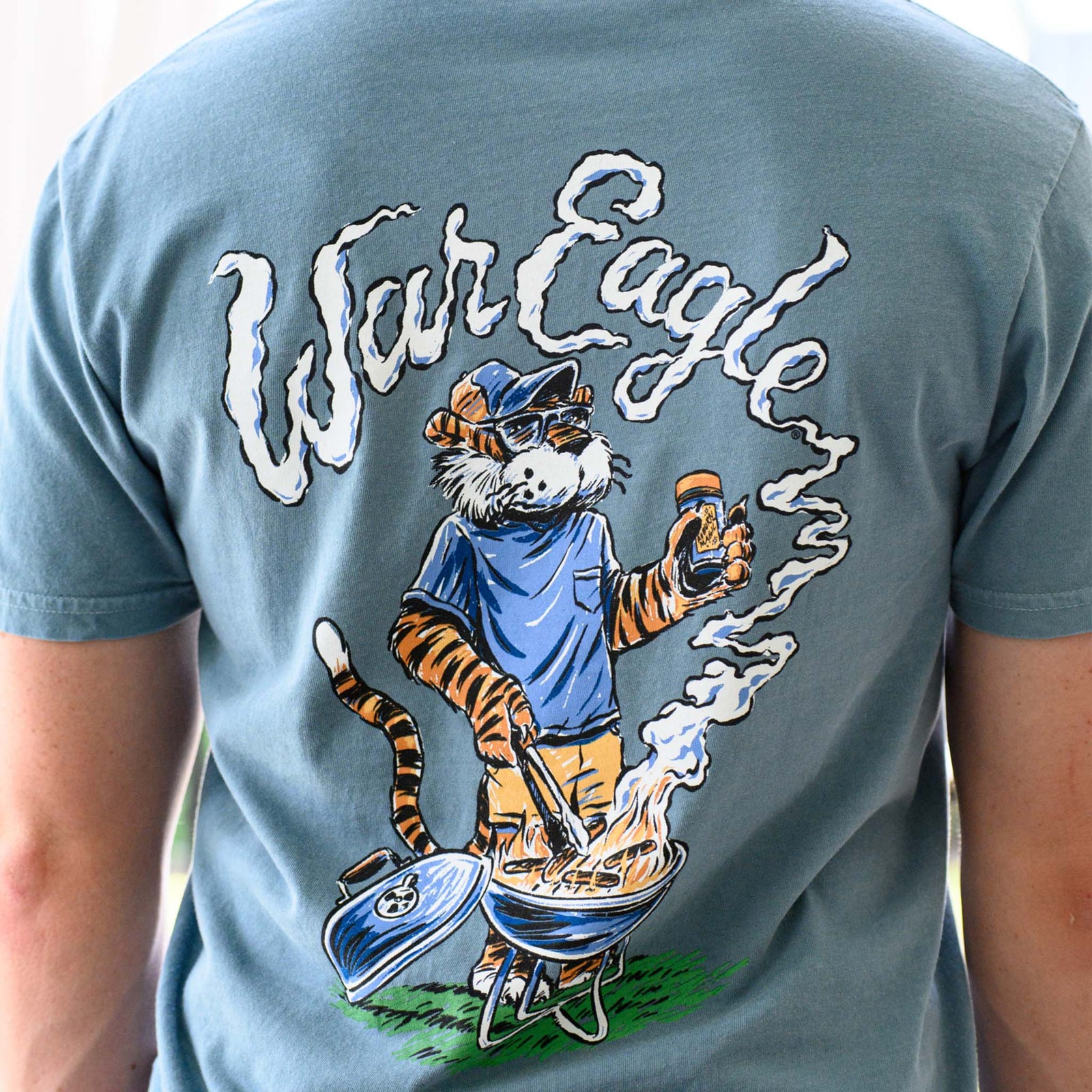 Back view of Auburn War Eagle Tailgate T-Shirt with Aubie the Tiger grilling, holding seasoning, and “War Eagle” lettering in smoke.