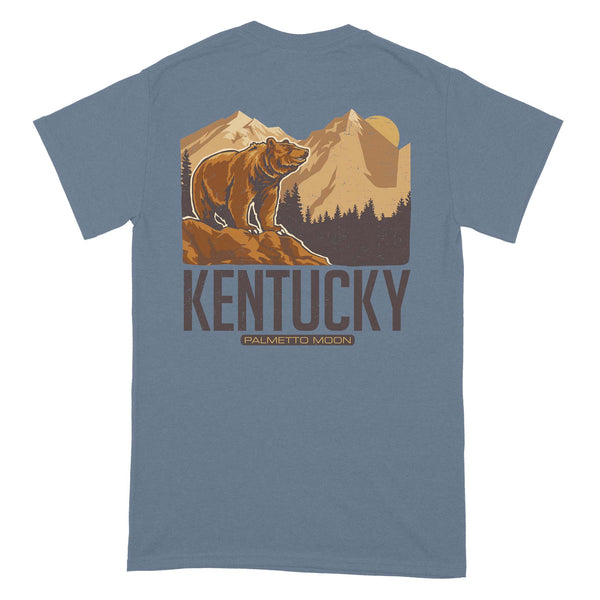  Back of indigo blue short sleeve t-shirt with brown bear graphic, mountain background, and large “Kentucky” text.