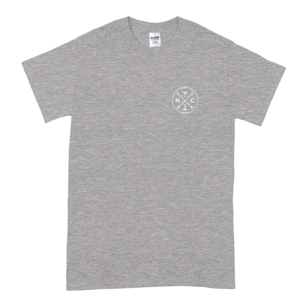  Palmetto Moon violet t-shirt with front chest graphic showing NC letters, lighthouse, crossed arrows, palm tree, and crescent moon inside a circle.