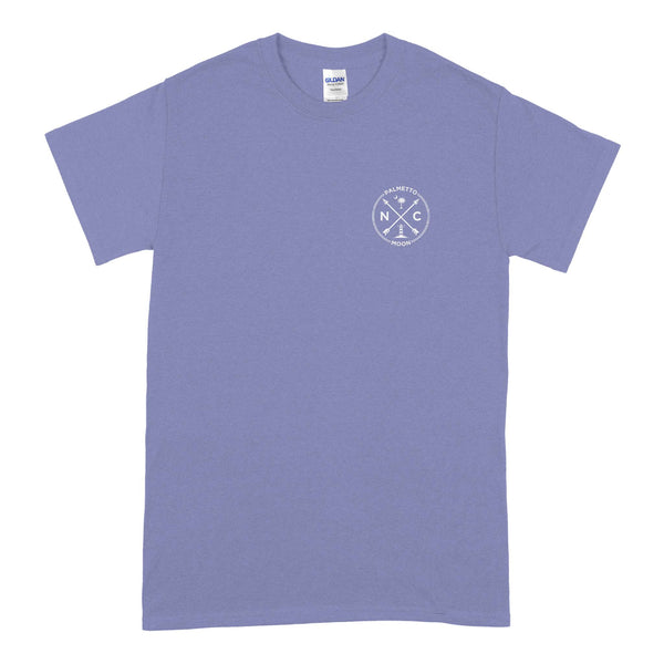  Palmetto Moon violet t-shirt with front chest graphic showing NC letters, lighthouse, crossed arrows, palm tree, and crescent moon inside a circle.