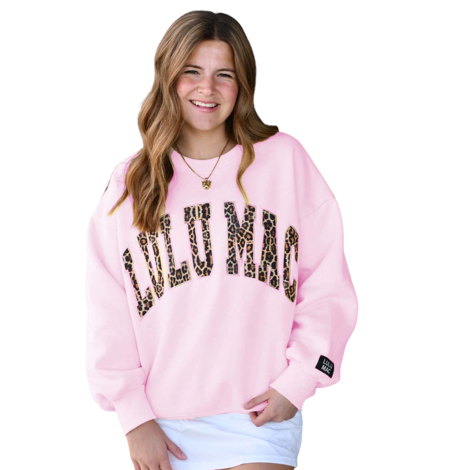 Person wearing a pink sweatshirt with leopard print text on a white background