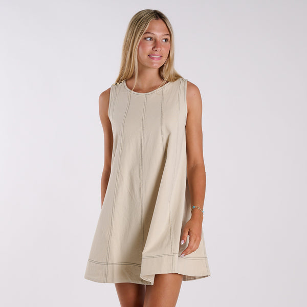 Woman wearing a beige sleeveless dress against a white background