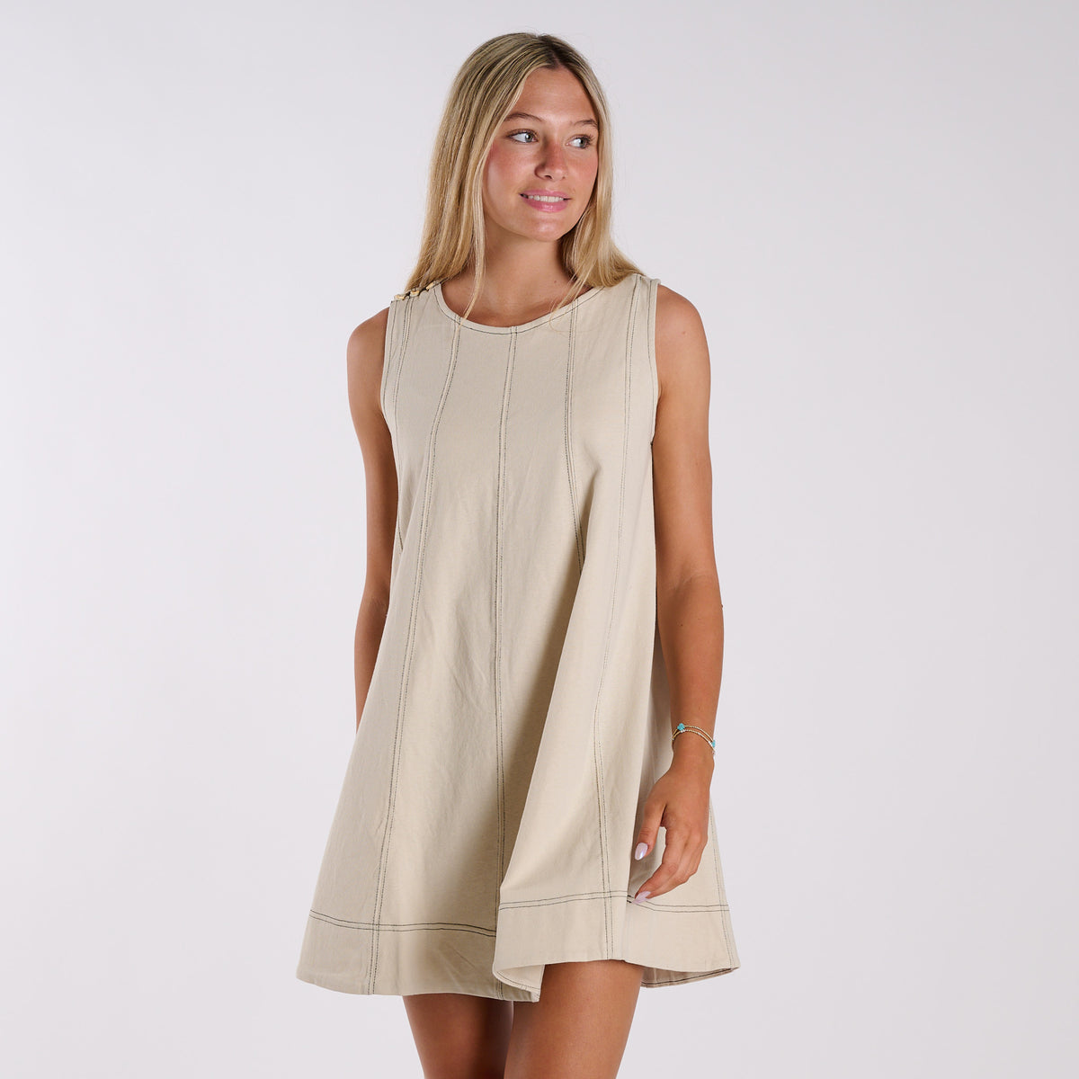 Woman wearing a beige sleeveless dress against a white background