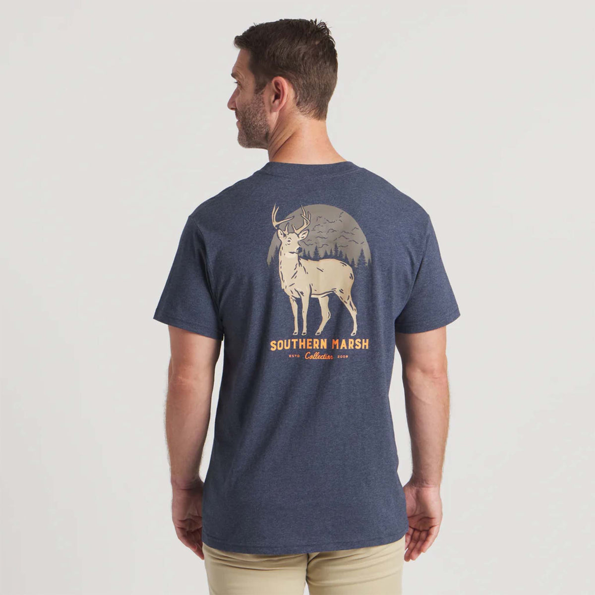 Man wearing navy Southern Marsh short sleeve tee with large buck graphic and forest background design on the back.