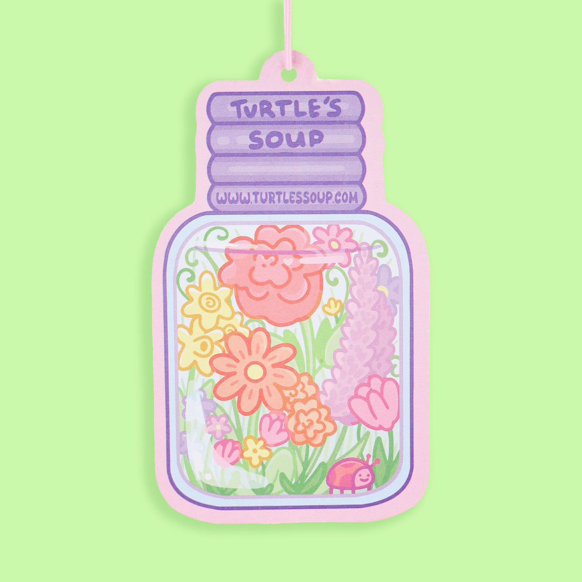 Decorative air freshener shaped like a jar with flowers on a green background