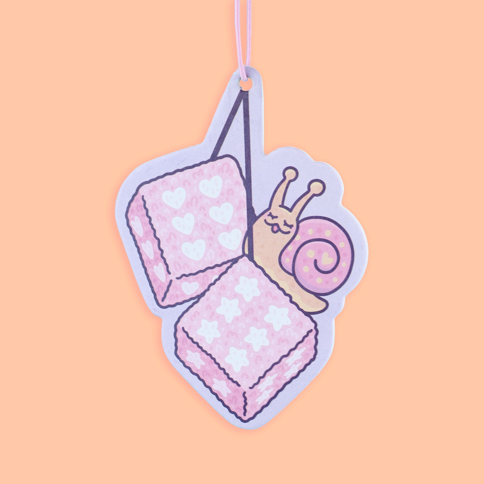 Pastel pink and purple air freshener with a snail design on a peach background