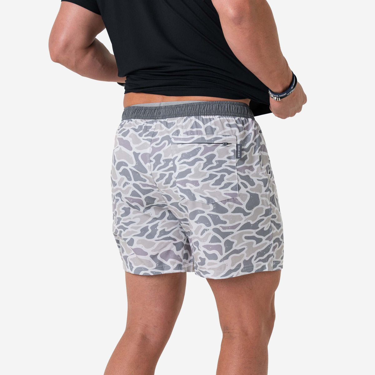 Person wearing camouflage shorts on a white background