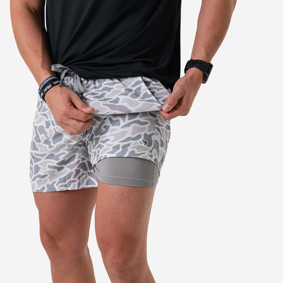 Person wearing gray camouflage athletic shorts on a white background