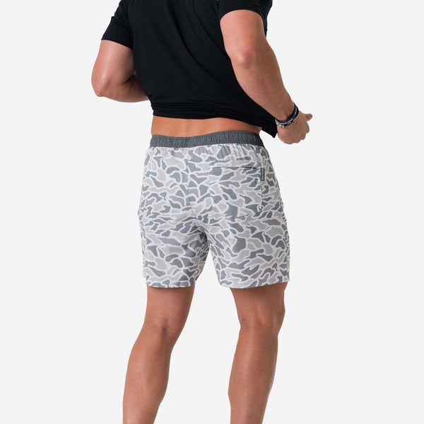 Person wearing gray camouflage shorts on a white background