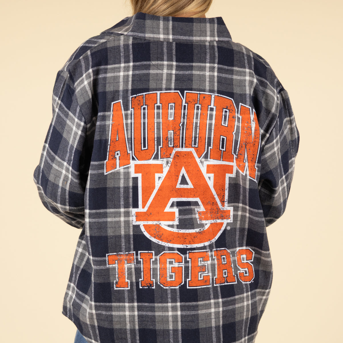 Plaid shirt with 'Auburn Tigers' text on the back against a beige background