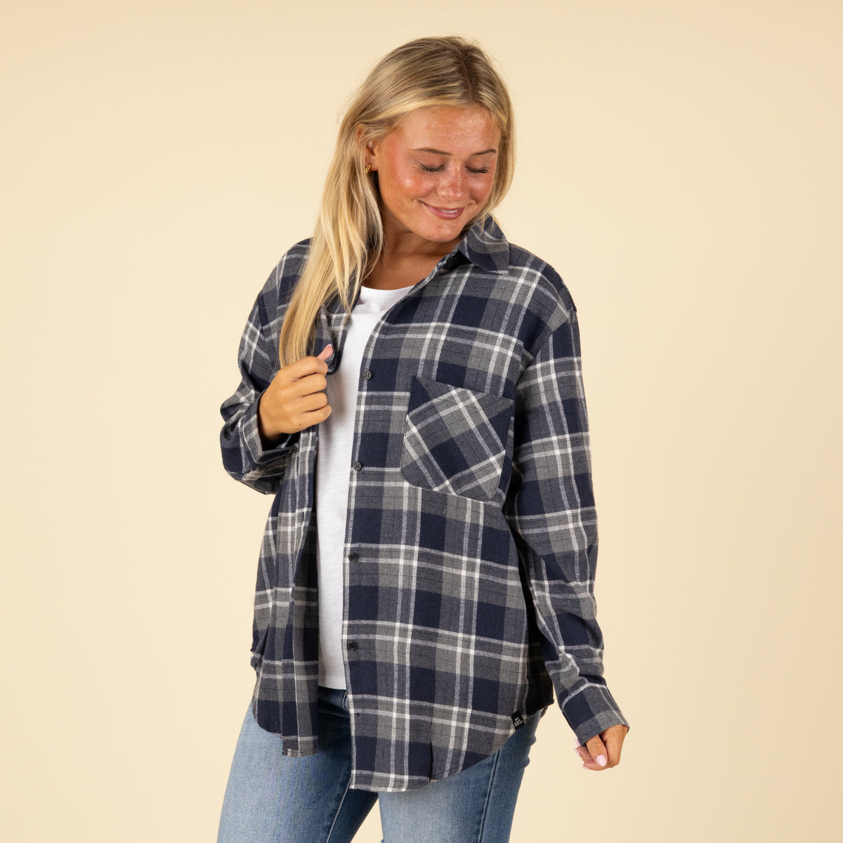 Woman wearing a blue plaid shirt against a beige background