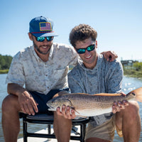 Two men posing for a picture with a fish on a boat.