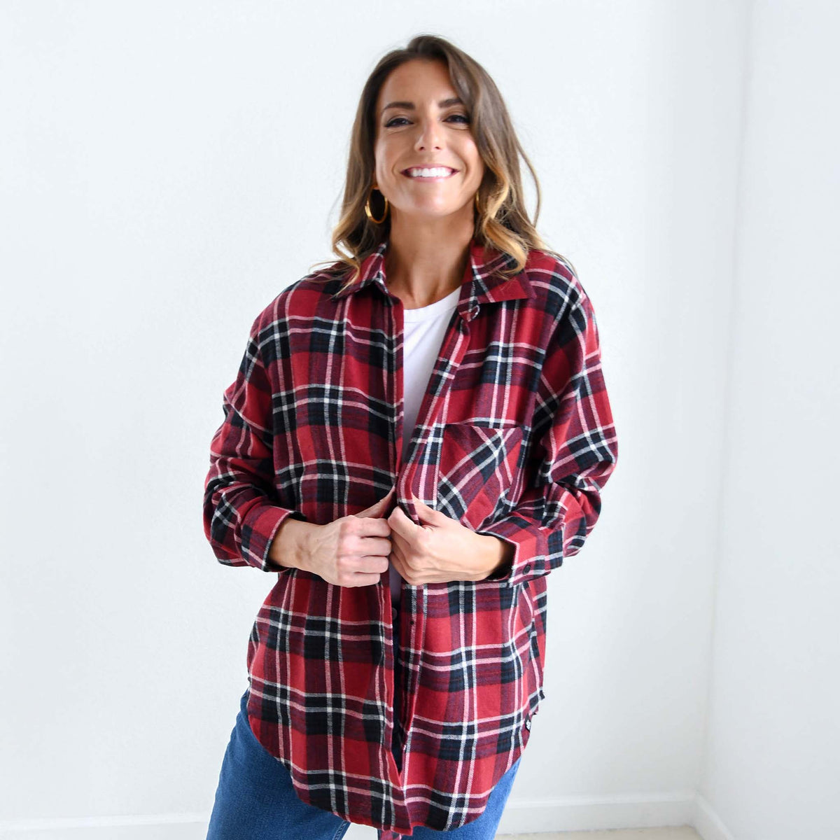 Front view of woman smiling while wearing red and black plaid flannel shirt over a white tee.