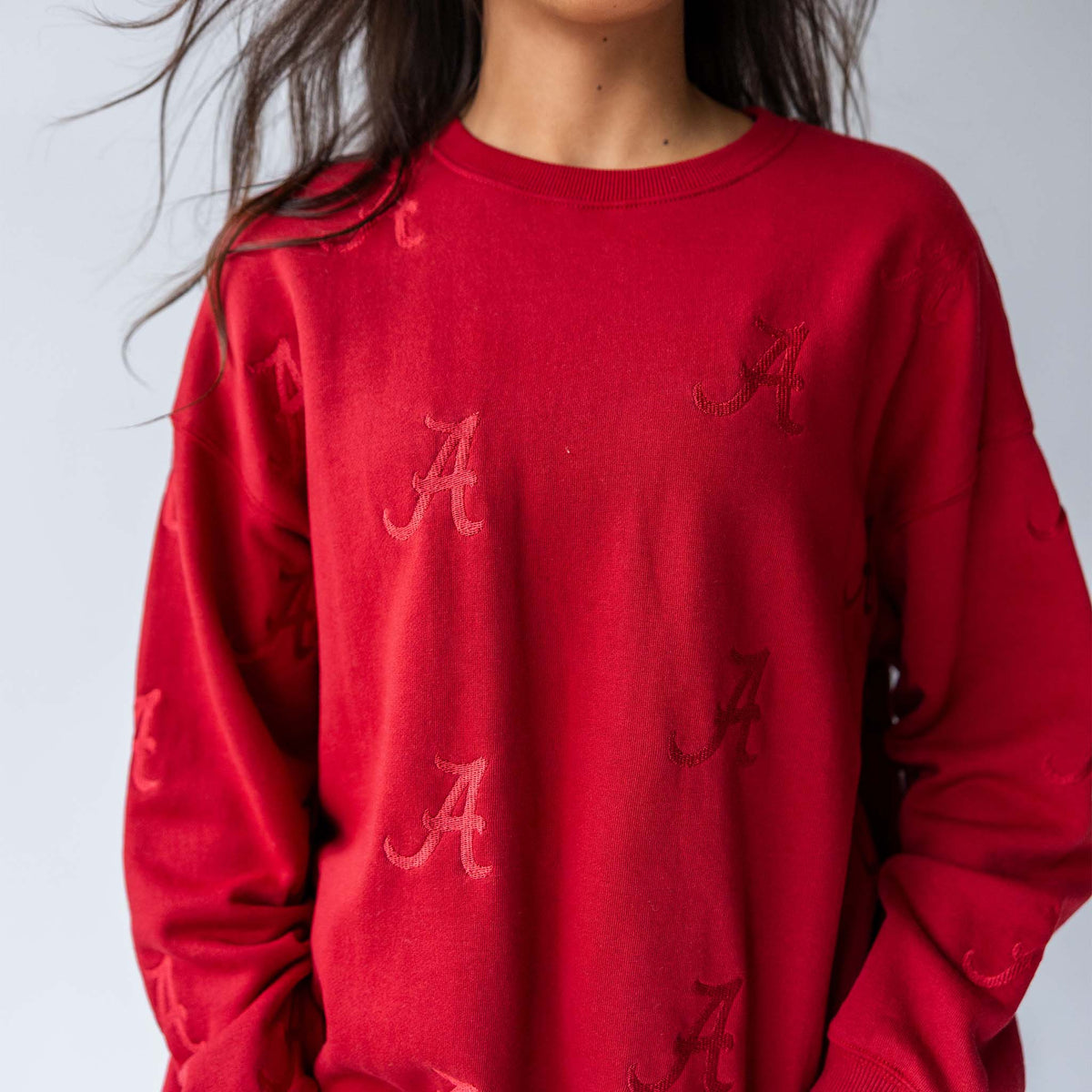 Close-up of crimson crewneck sweatshirt showing tonal Alabama “A” embroidery on the chest.
