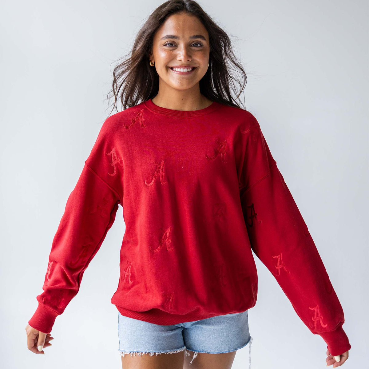 Woman wearing a crimson crewneck sweatshirt with tonal Alabama “A” embroidery, facing forward and smiling.