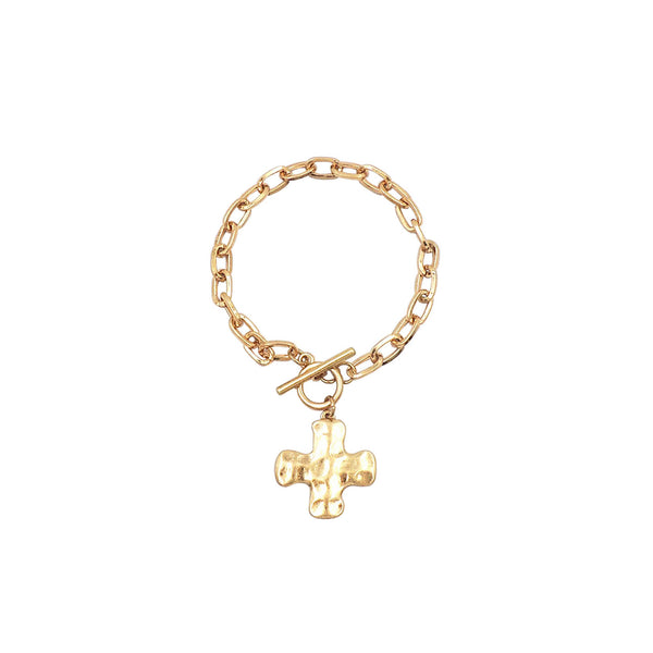Gold chain link bracelet with toggle clasp and hammered cross pendant displayed on a white background.