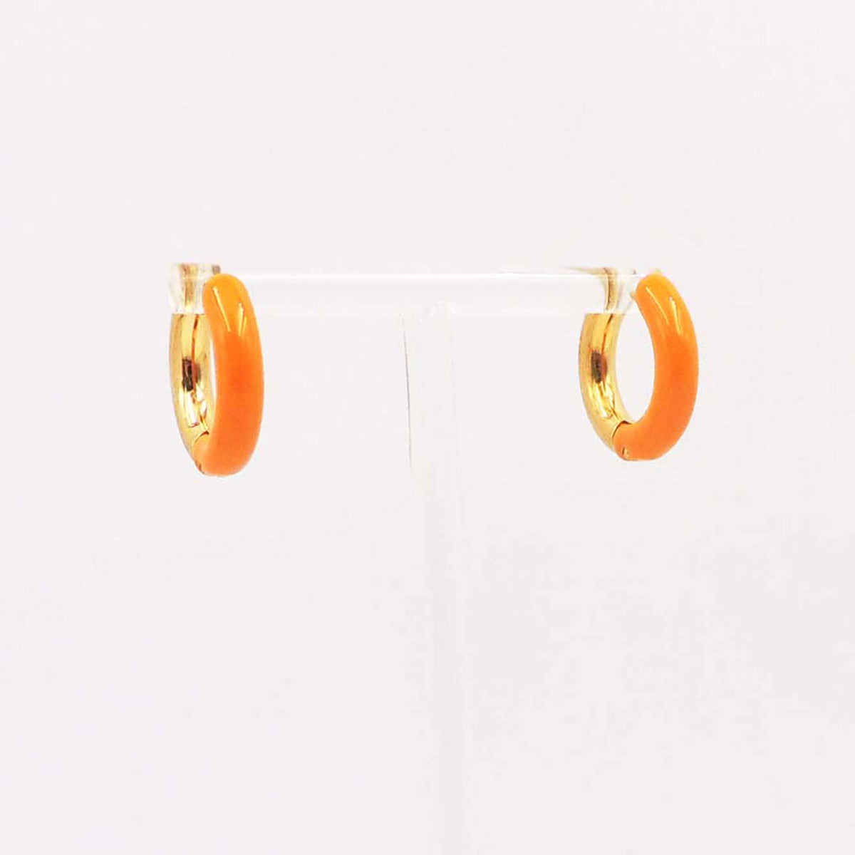 Pair of small orange enamel hoop earrings with gold-tone interior displayed on a clear stand.