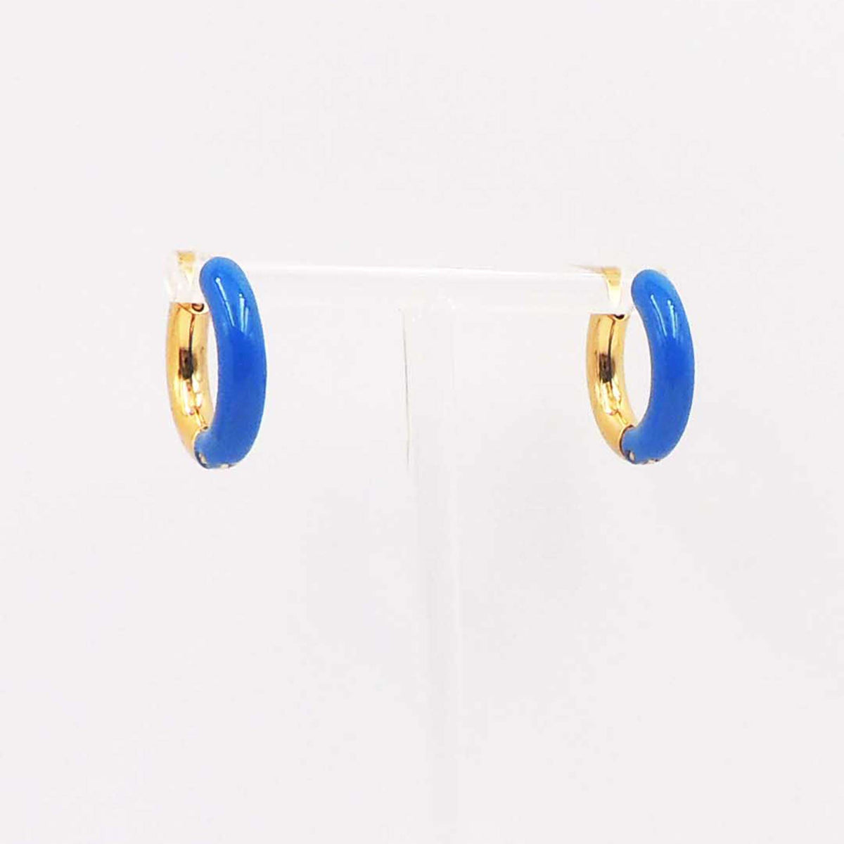 Pair of small gold-tone hoop earrings with glossy blue enamel accents displayed on a clear stand.