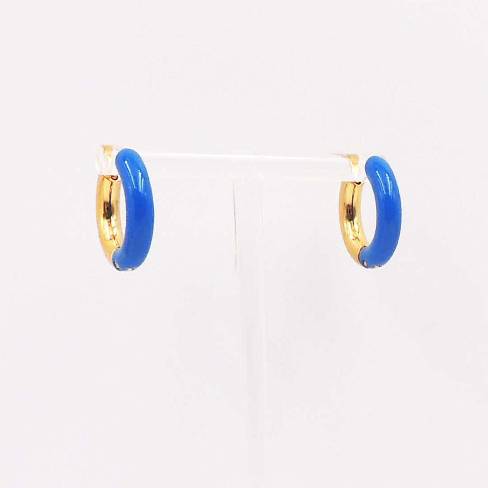 Pair of small gold-tone hoop earrings with glossy blue enamel accents displayed on a clear stand.