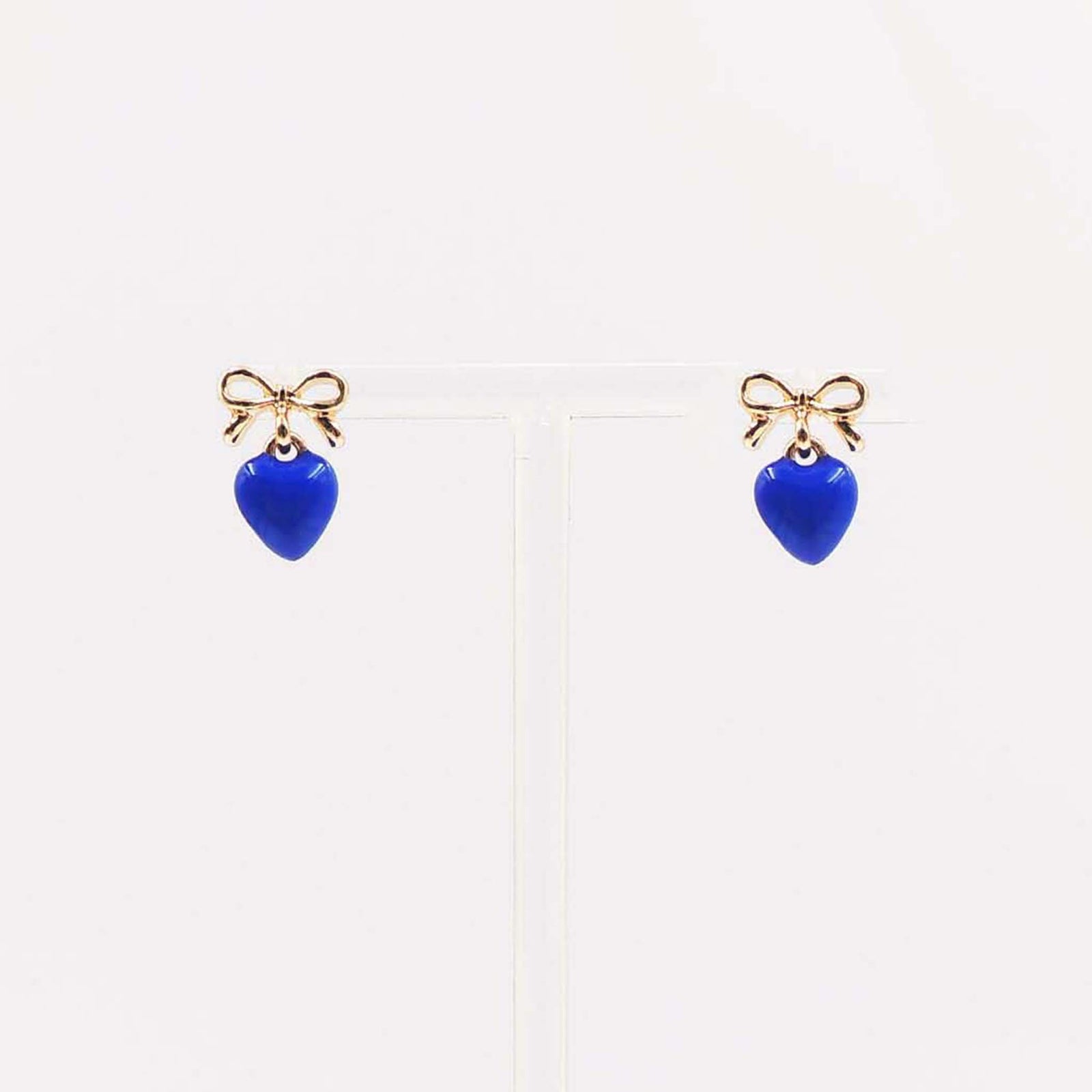 Gold bow stud earrings with dangling royal blue enamel heart charm.