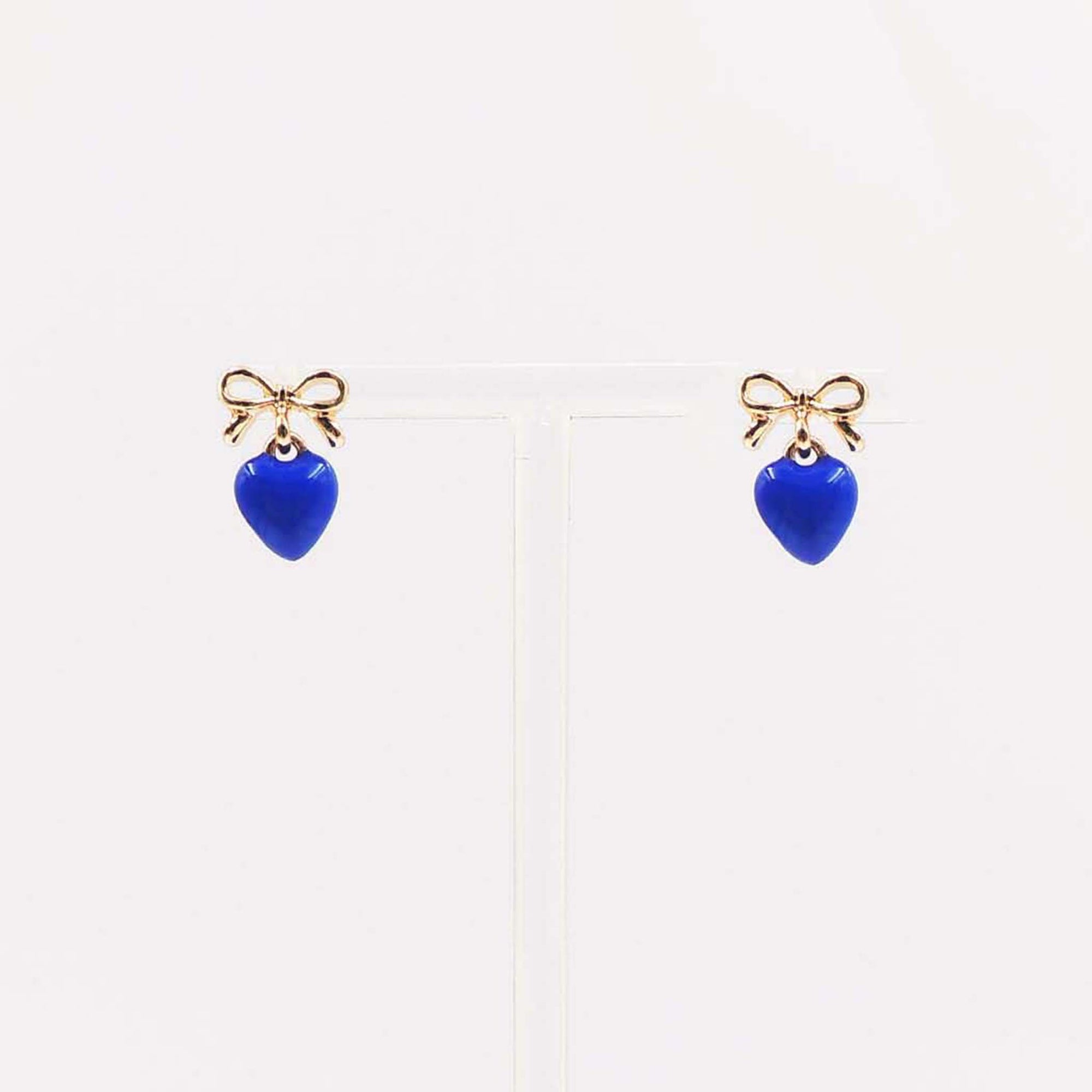 Gold bow stud earrings with dangling royal blue enamel heart charm.