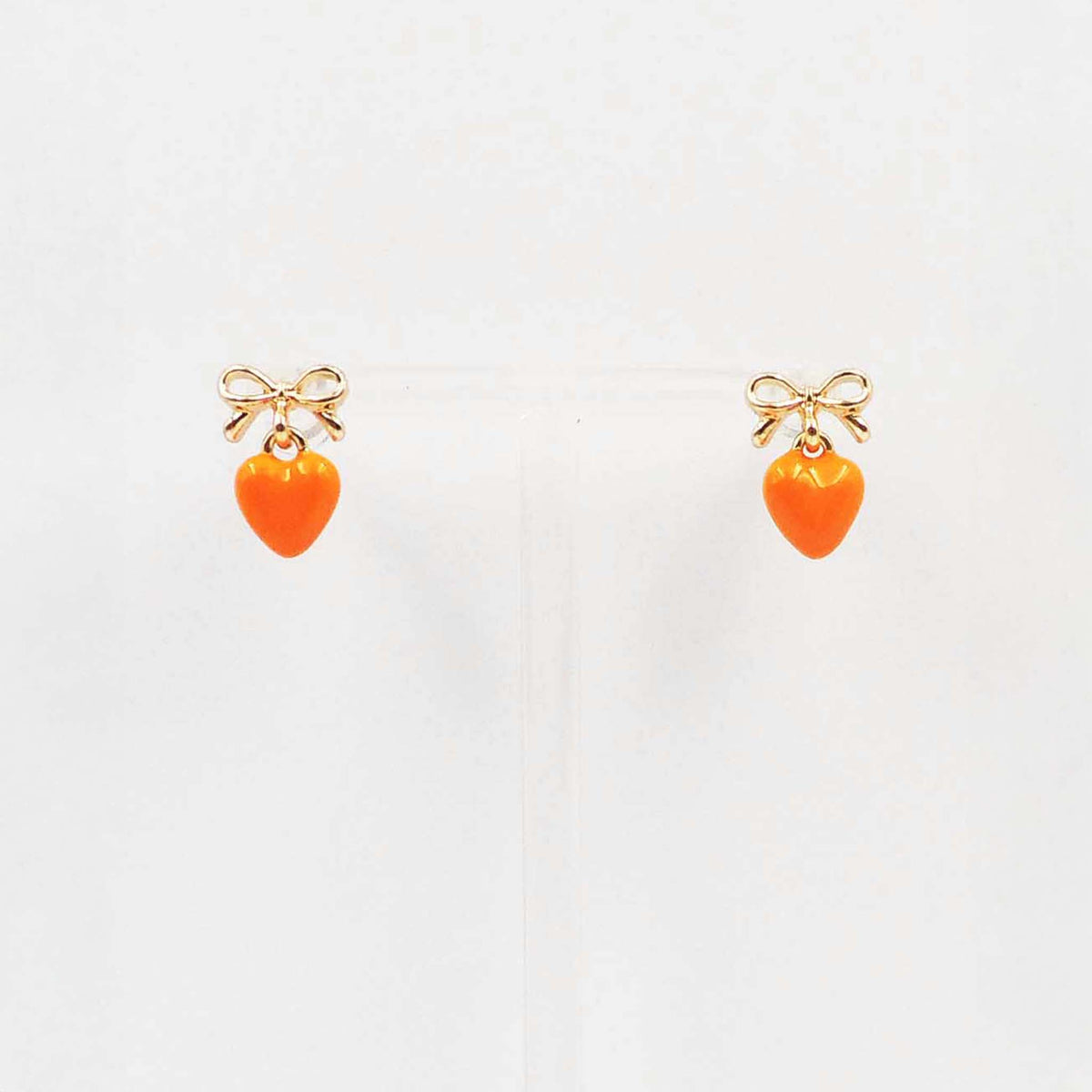Gold bow stud earrings with dangling orange enamel heart charm.